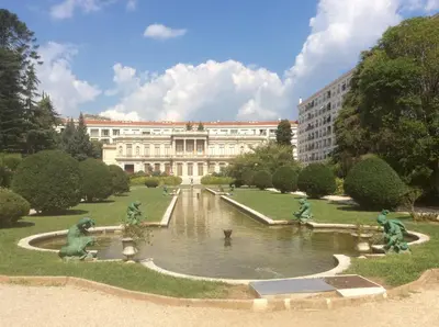 a building with a fountain in the middle of a garden at Les Grands Cedres D3 in Nice