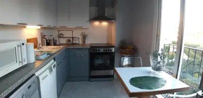 a kitchen with white cabinets and a counter top with a table at Les Grands Cedres D3 in Nice