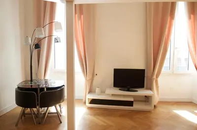a living room with a television and a table with a chair at AzurAppart Elegant Studio Centre in Nice