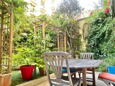 a wooden table and chairs in a garden at Homelivia, Luxueux Appartement avec Jardin privé in Nice