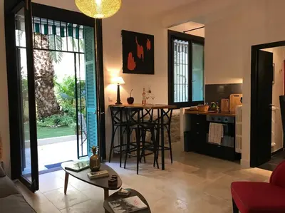a living room with a table and a kitchen at Homelivia, Luxueux Appartement avec Jardin privé in Nice