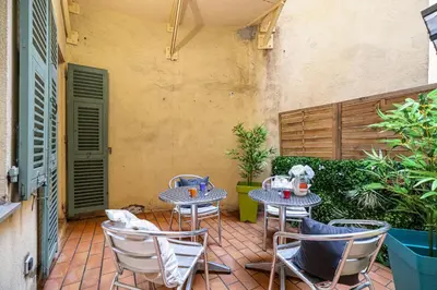two tables and chairs on a patio with plants at Large one bedroom flat in the Old Town in Nice