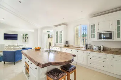 a kitchen with white cabinets and a wooden table at Semiramis in Villefranche-sur-Mer