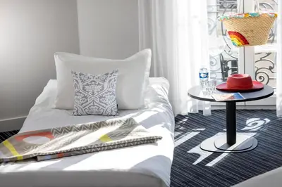 a bedroom with a bed with a table and a window at Hotel 66 Nice in Nice