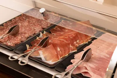 a tray of meat and meats on a stove with tongs at Hotel 66 Nice in Nice