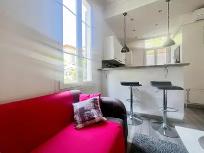 a living room with a red couch and two stools at Proche promenade des anglais et de la mer in Nice