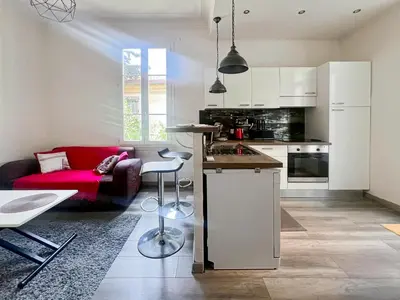 a kitchen and living room with a red couch at Proche promenade des anglais et de la mer in Nice