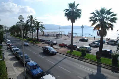 a street with cars parked in a parking lot with palm trees at Hôtel Azur in Nice