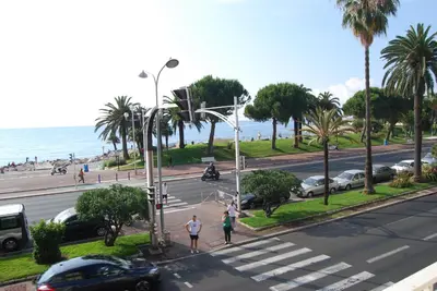two people walking down a street near the ocean at Hôtel Azur in Nice