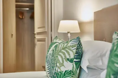 a bed with green and white pillows and a lamp at La Résidence de La Réserve in Beaulieu-sur-Mer