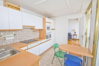 a kitchen with white cabinets and a table and chairs at PROMENADE HOLIDAY - ORIENT & SEA in Nice
