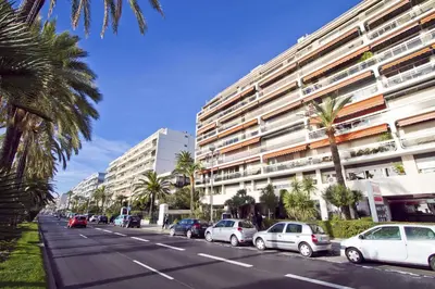 a street with cars parked in front of a large building at PROMENADE HOLIDAY - COSY SEA FRONT STUDIO in Nice