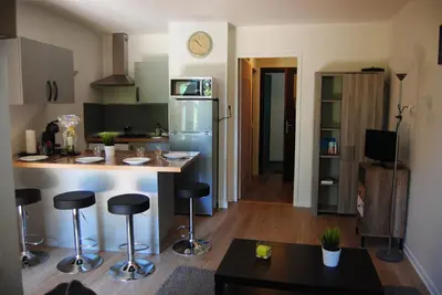 a kitchen with a refrigerator and a counter with bar stools at Les Palmiers à 700m de la mer in Nice