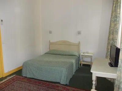 a small bedroom with a bed and a television at Hotel Marcellin in Beaulieu-sur-Mer