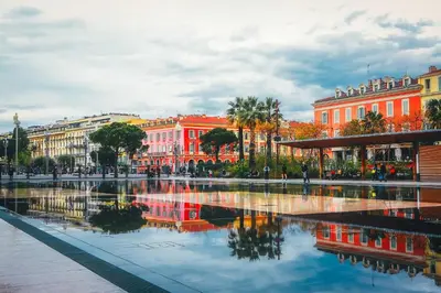 a city with buildings and a reflection in the water at F2 Centre - Gare in Nice