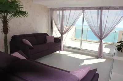 a living room with a couch and a large window at Appartement 3 pièces Nice Promenade des anglais dernier étage vue mer solarium in Nice