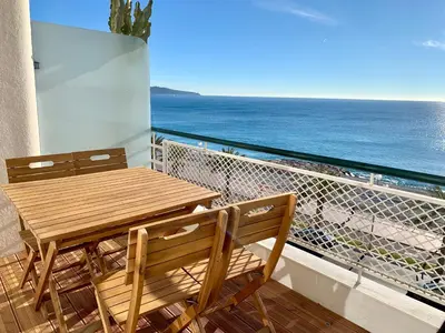 a wooden table and chairs on a balcony with the ocean at Florida Blue - Easy Home Booking in Nice