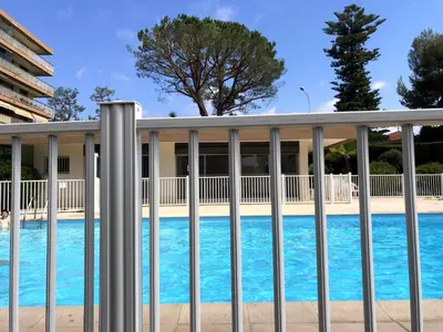 a pool behind a fence with blue water at Oasis Méditerranéen Piscine & Parking Calme absolu in Nice