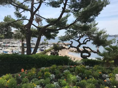 a view of a beach with trees and flowers at Les Jasmins in Beaulieu-sur-Mer