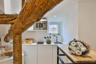 a kitchen with white cabinets and a table with flowers on it at MY CASA - LA CIVETTE - Place Garibaldi in Nice