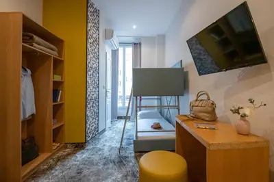 a room with a chair and a desk and a table at Hotel d'Ostende in Nice