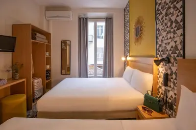 a hotel room with two beds and a window at Hotel d'Ostende in Nice