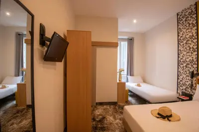 a hotel room with two beds and a television at Hotel d'Ostende in Nice