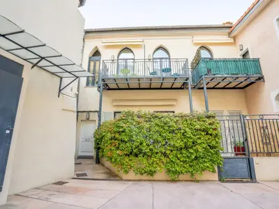 a building with a balcony and a bush in front of it at Apartment Wilson by Interhome in Nice