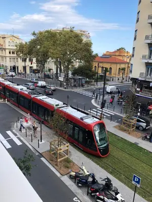 a red train traveling down a city street at Palais des domes in Nice