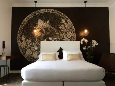 a bedroom with a white bed with a large wall at Hotel Villa Rose in Nice