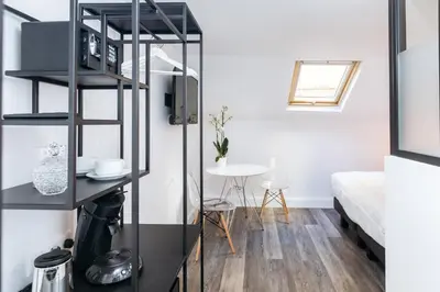 a room with a bed and a black book shelf at Arome Hôtel in Nice