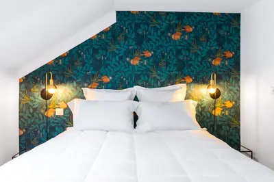 a bedroom with a large white bed with a tropical wallpaper at Arome Hôtel in Nice