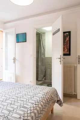 a white bedroom with a bed and a shower at Place du Pin in Nice