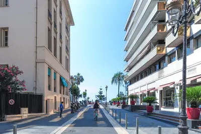 two people riding bikes down a street next to buildings at Studio Massenet Five stars holiday house in Nice