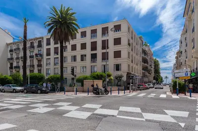 a large white building on a city street with a palm tree at Nice Appart in Nice