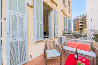 a balcony with a bench and a table and a bottle of wine at CARRE D'OR TERRACE AP4015 NICE by Riviera Holiday Homes in Nice