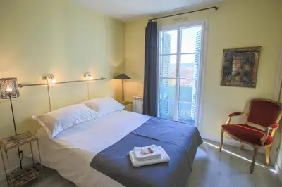 a bedroom with a bed and a chair and a window at La Providence Nice in Nice