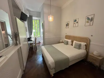 a small room with a bed and a table and a window at Nice Garden Hotel in Nice