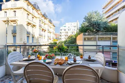 a table with chairs and food on a balcony at LE FRANCE-MASSENET AP3015 by Riviera Holiday Homes in Nice