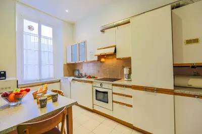 a kitchen with white cabinets and a table with a bowl of fruit at VIA ITALIA AP1054 - By Riviera Holiday Homes in Nice