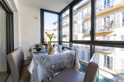 a dining room with a table and chairs and large windows at JARDINS MASSENA AP4088 Nice, by Riviera Holiday Homes in Nice