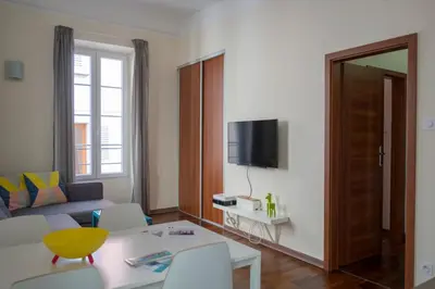 a living room with a couch and a tv on a wall at Magnifiques Appartements au coeur du Vieux Nice in Nice