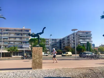 a man walking past a statue of a man dancing at Charmant 2 pièces à 50 M de la mer in Cros-de-Cagnes