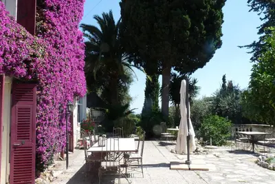 a patio with purple flowers and a table and an umbrella at Castel Enchanté in Nice