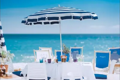 a table with chairs and an umbrella on the beach at Unique sea view apartment, center, 100m2 in Nice