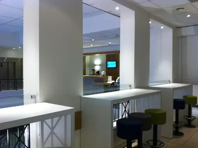 an office lobby with white countertops and green stools at ibis budget Nice Aeroport in Nice