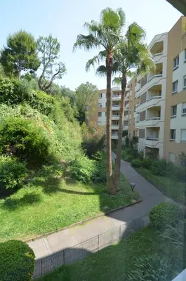 a palm tree and a sidewalk in front of a building at PLEIN CIEL - Appartement 5 personnes avec piscine sur la Corniche Fleurie à Nice in Nice