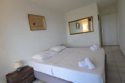a bedroom with a bed with white sheets and a mirror at PLEIN CIEL - Appartement 5 personnes avec piscine sur la Corniche Fleurie à Nice in Nice