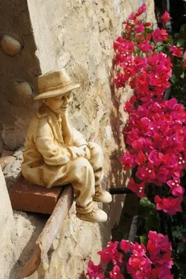 a statue of a man sitting on a bench next to flowers at Chambres d'hôtes Les Terrasses du Soleil in Cagnes-sur-Mer