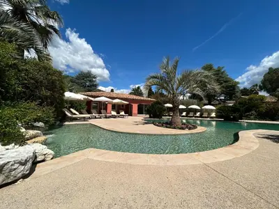 a swimming pool in front of a house with palm trees at Domaine De Respelido in Carros